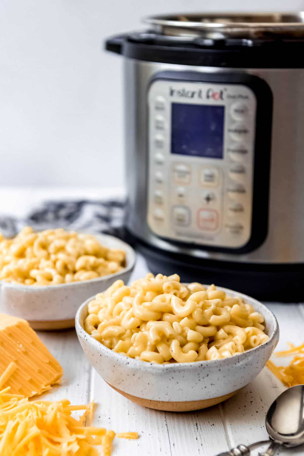 two bowls of homemade macaroni & cheese in front of an Instant Pot pressure cooker.
