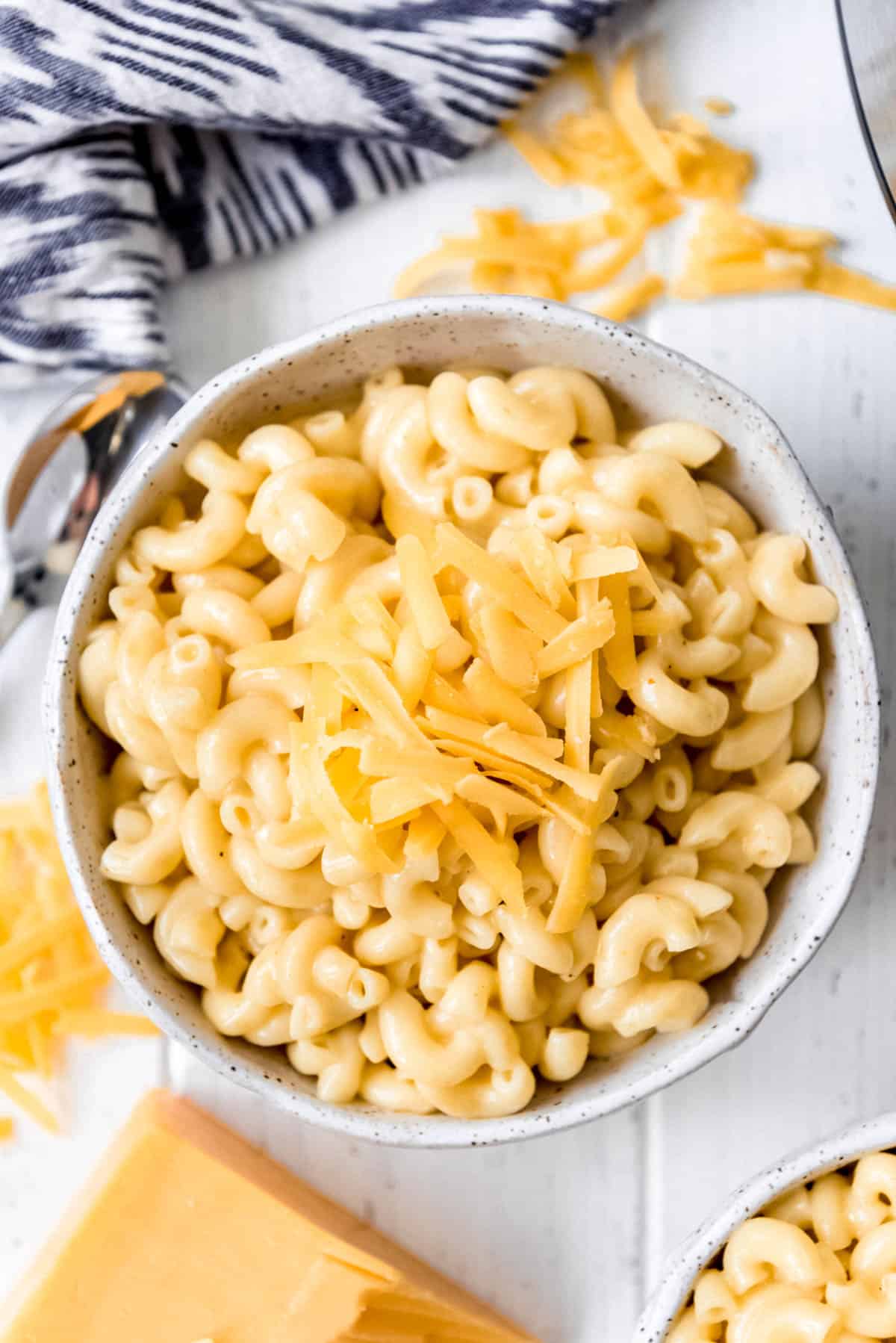 a bowl full of homemade creamy macaroni & cheese topped with freshly grated cheddar cheese.