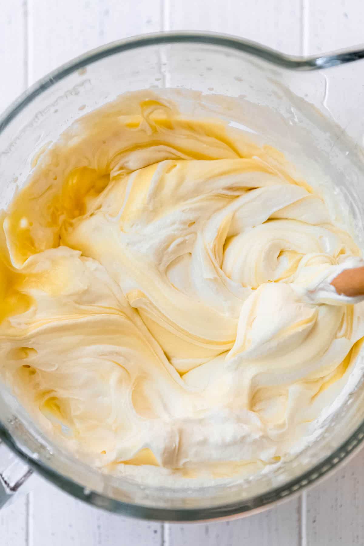 whipped cream folded into vanilla pudding mixture in a glass bowl