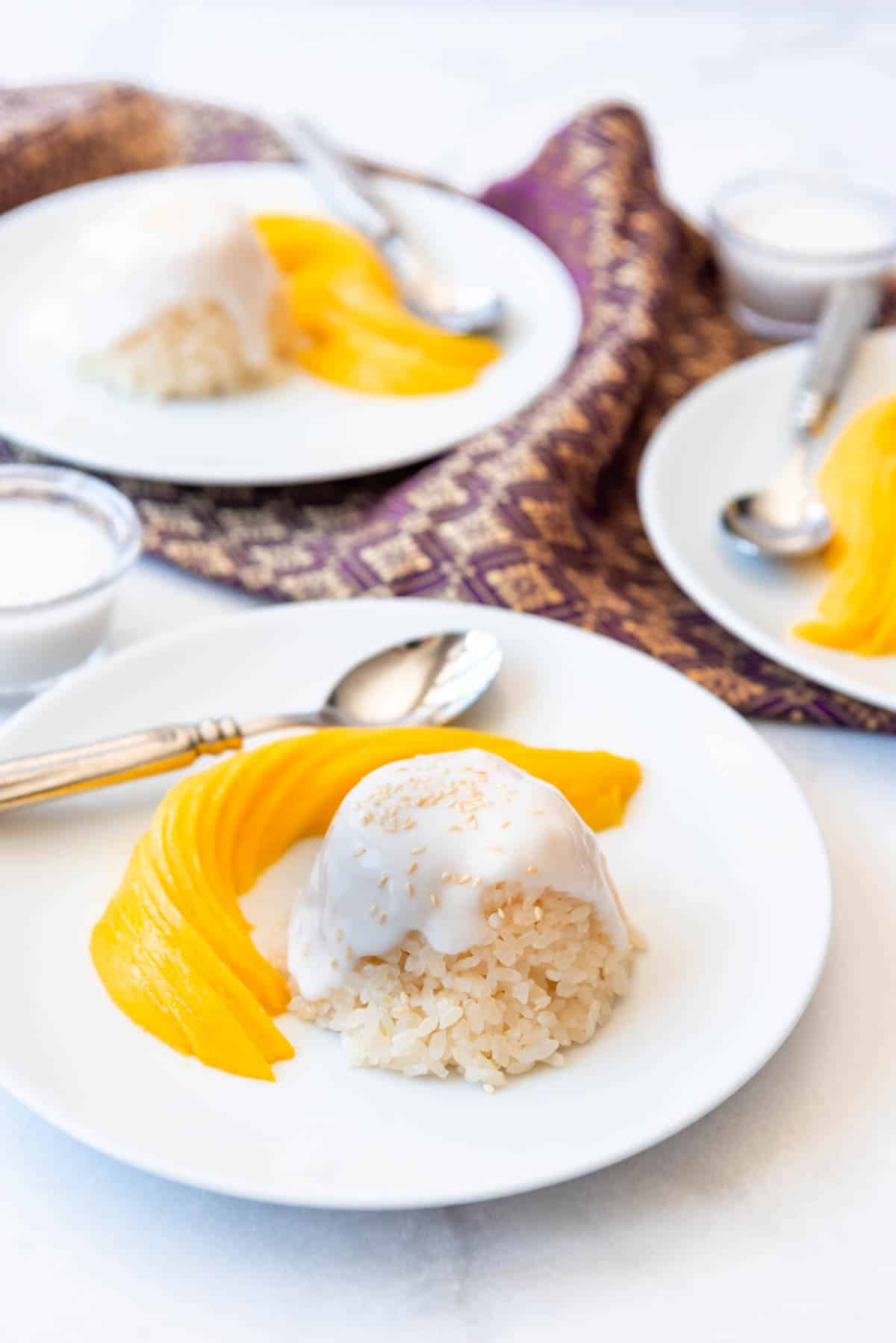 Mango Sticky Rice sevings on white plates on a table. 