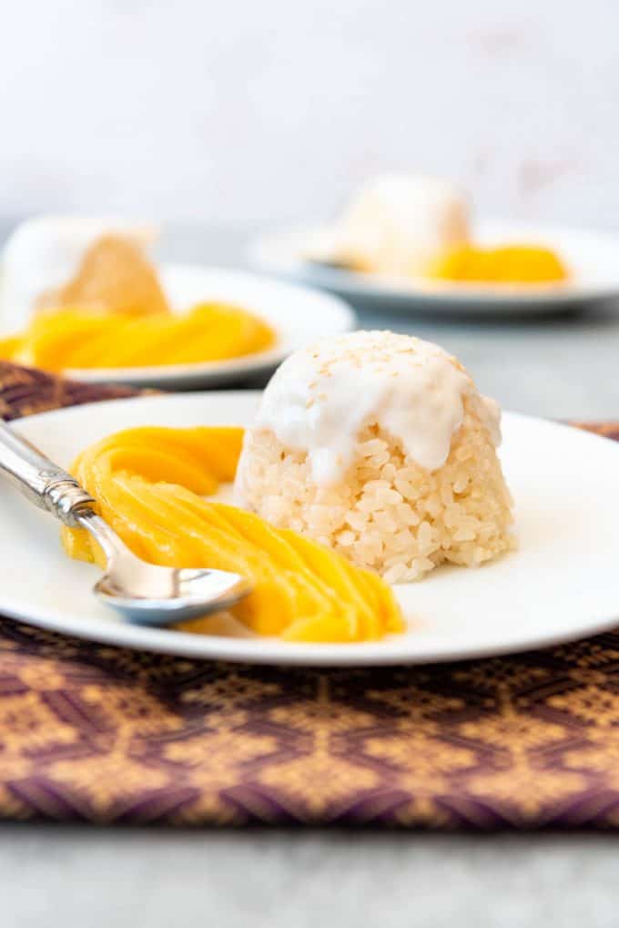 Close up of mango sticky rice on a white plate.