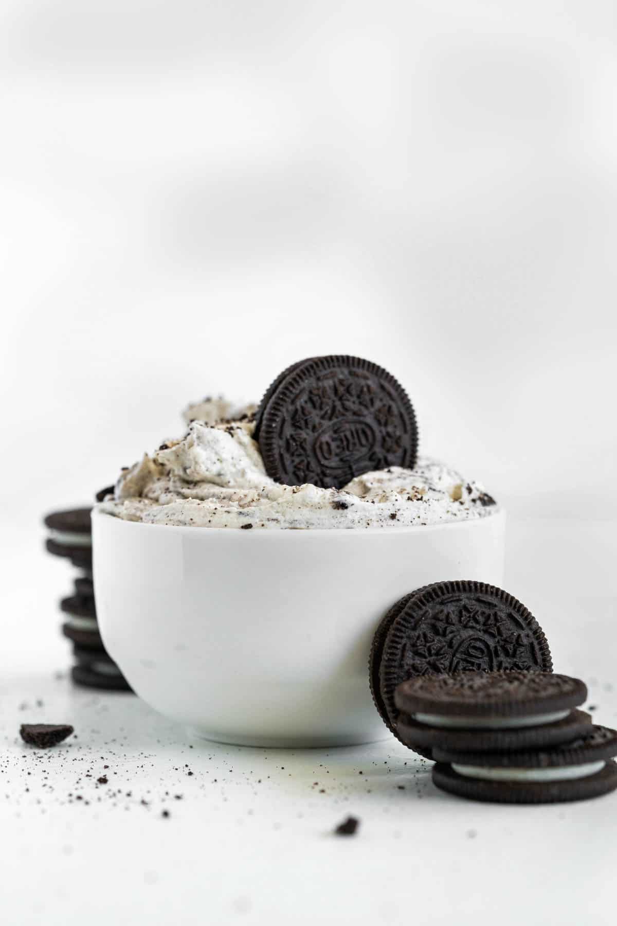 Oreo Dip in a white bowl with with Oreo cookies on a white table.