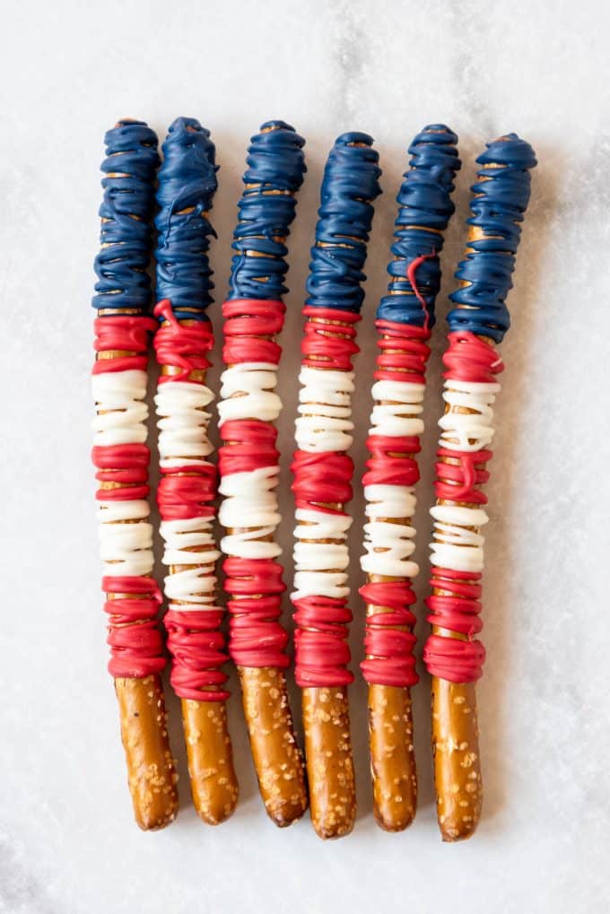 pretzel rods decorated with red, white, and blue melted white chocolate to look like American flags