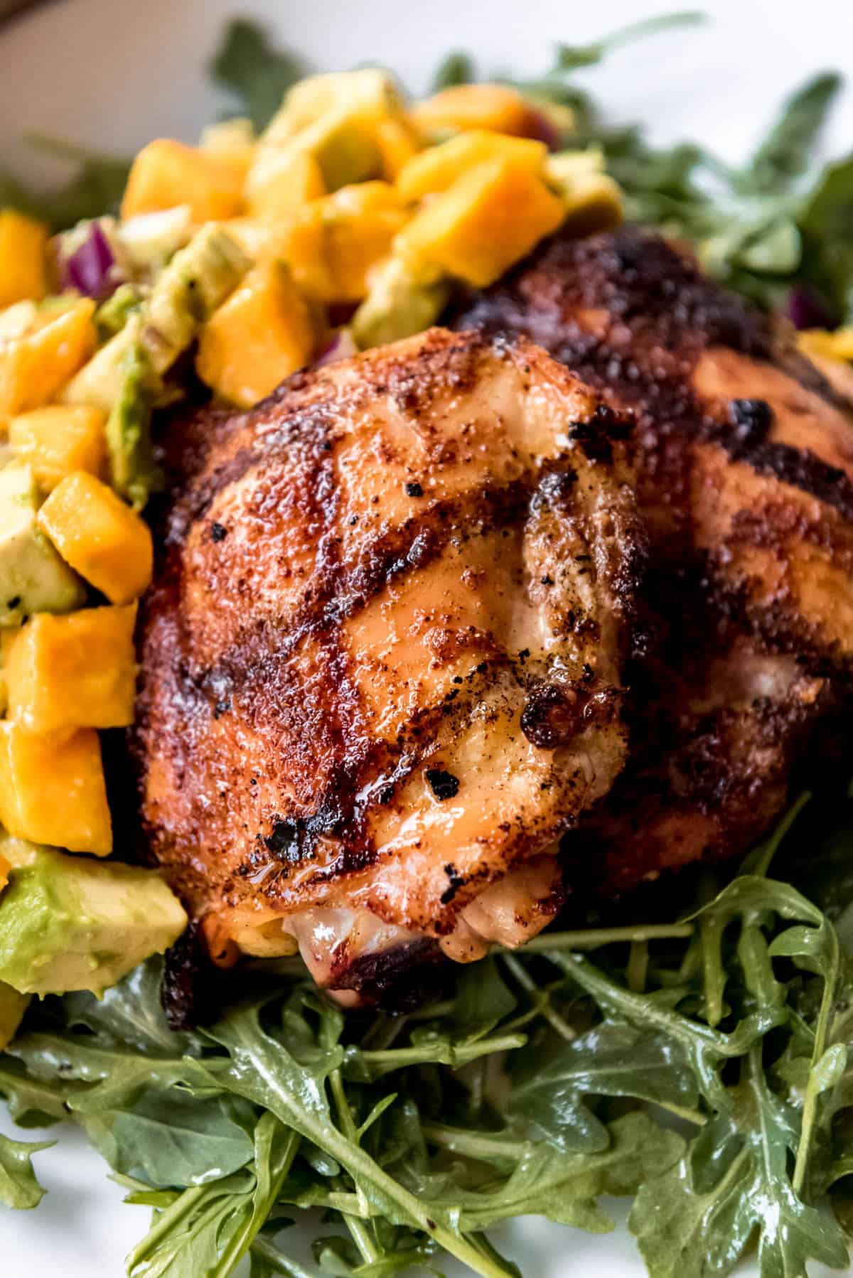 a close image of a grilled chicken thigh with spice rub and honey glaze