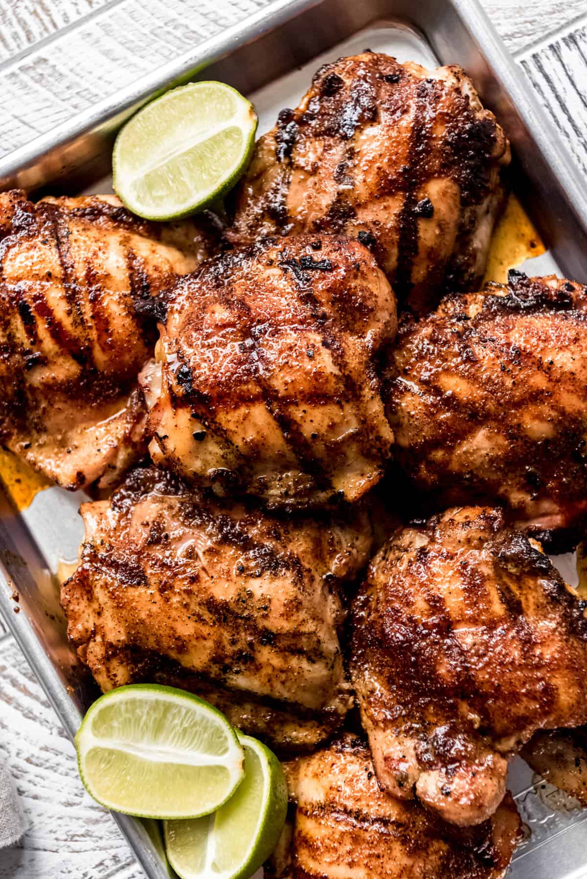 chicken thighs with grill marks next to sliced limes