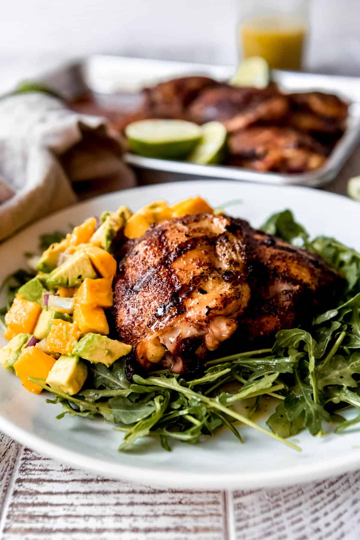 a plate of arugula salad, mango salsa, and grilled spicy honey chicken