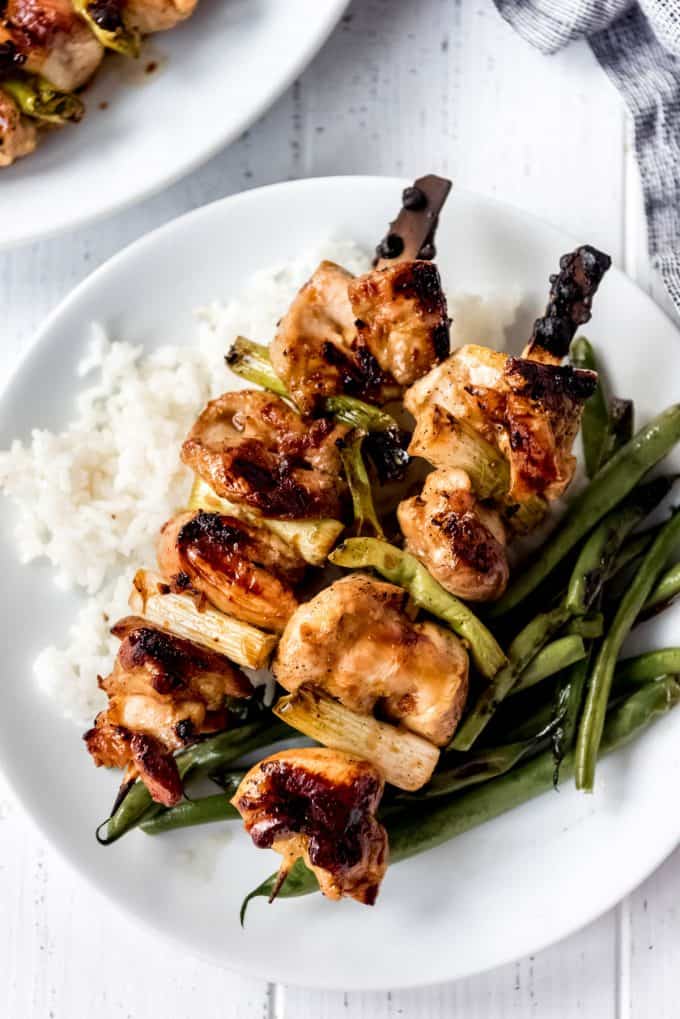 two yakitori Japanese grilled chicken skewers on a plate with white rice and roasted green beans