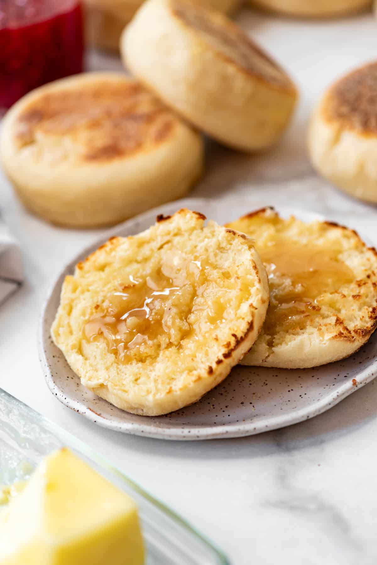 a sliced, toasted english muffin with butter and honey on it