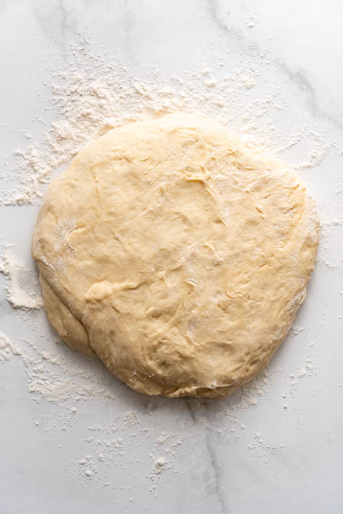 Punched down dough on a lightly floured surface.