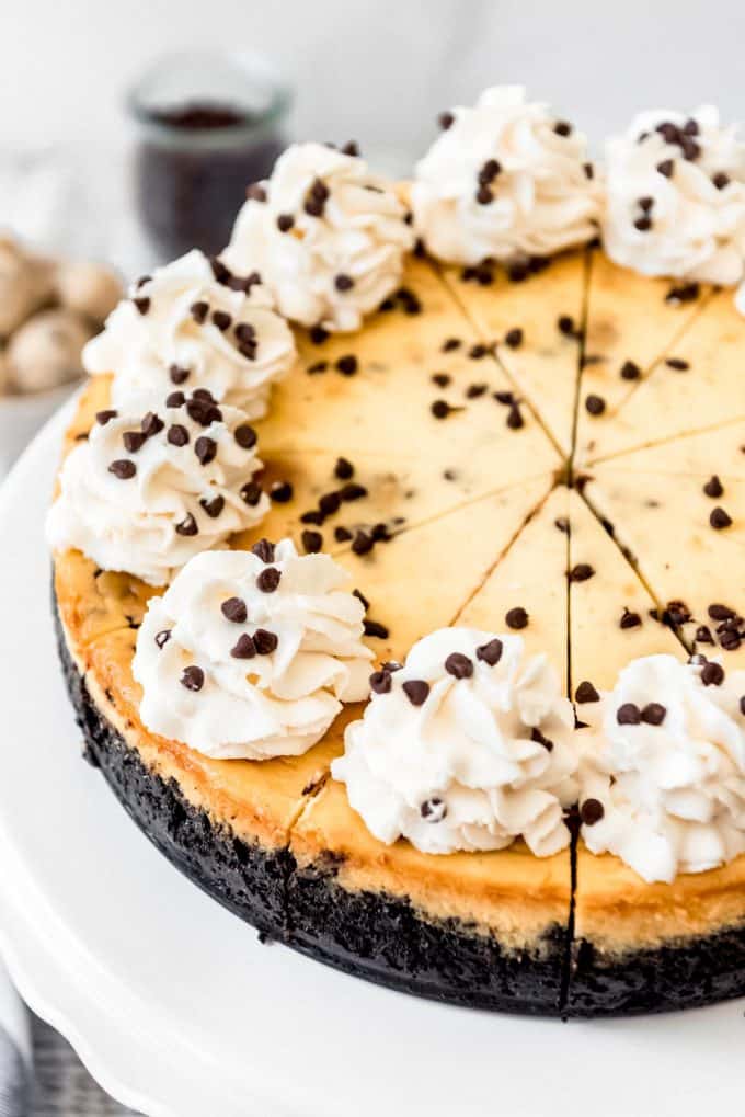 swirls of whipped cream on top of slices of chocolate chip cookie dough cheesecake