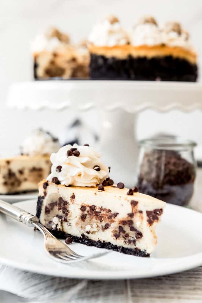 a slice of chocolate chip cookie dough cheesecake on a white plate with a fork