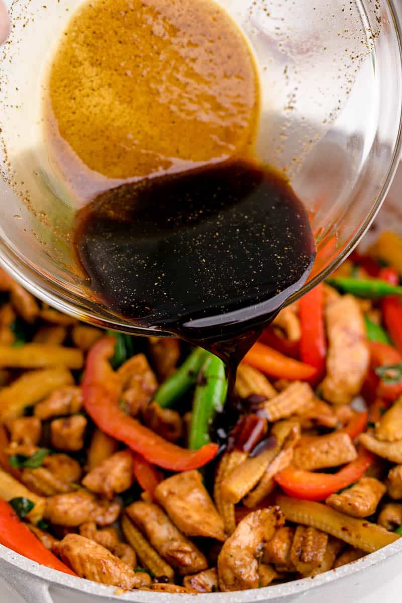Pouring soy sauce mixture over cooked chicken and veggies.