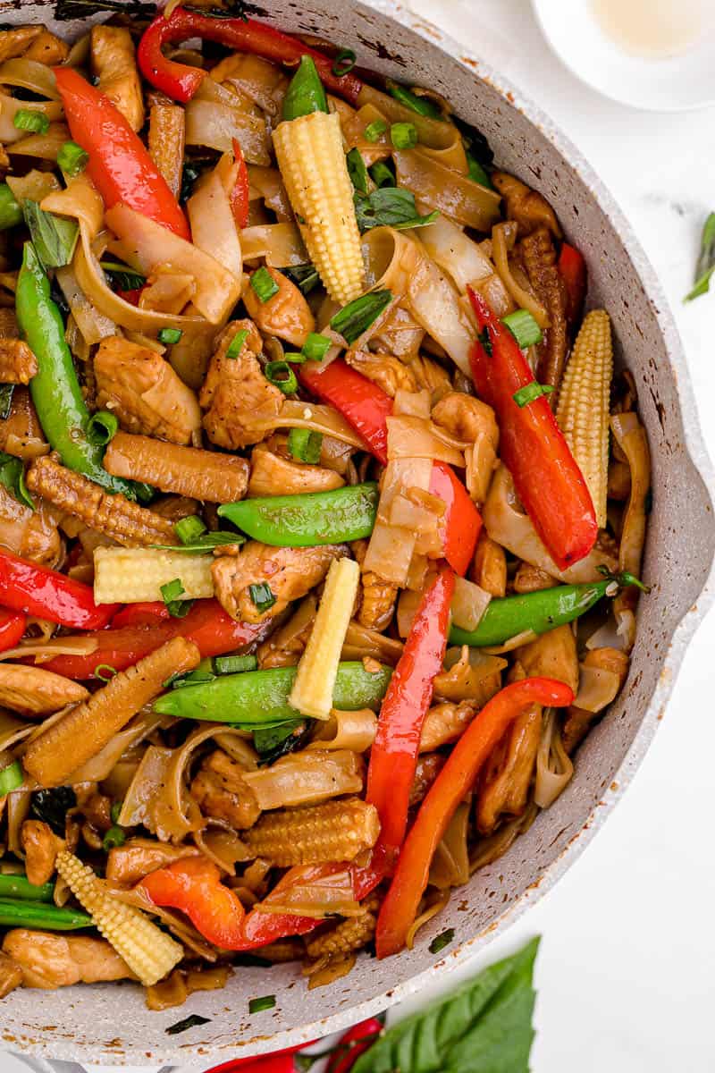 A close image of cooked noodles, chicken, and vegetables in a pan.
