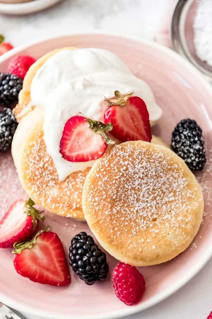 Japanese pancakes topped with powdered sugar, whipped cream, and fresh fruit