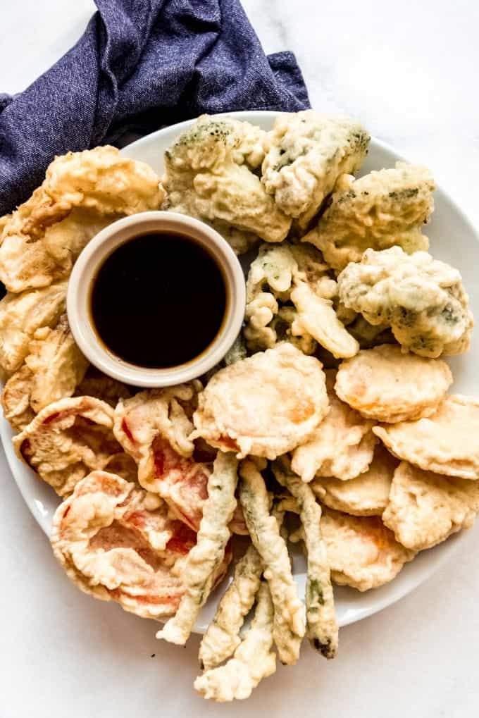 a plate full of vegetable tempura with a bowl of dipping sauce