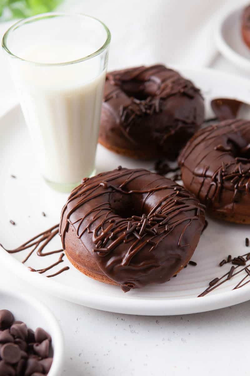 Chocolate donuts on a white plate with a glass of milk