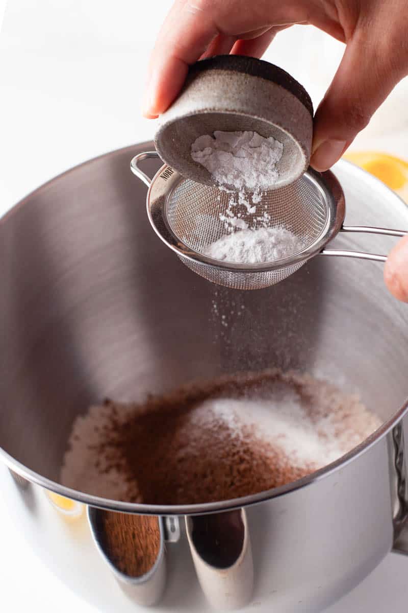 Baking powder is added to the flour and cocoa powder mixture, first through a small fine mesh strainer. 