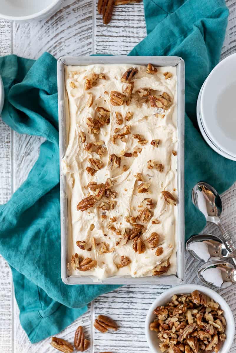 a bread pan full of butter pecan ice cream with toasted chopped pecans sprinkled on top