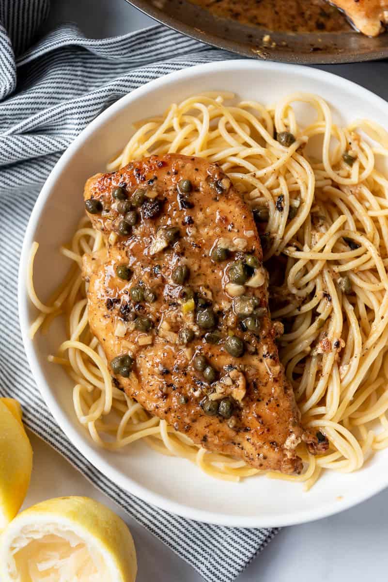 a piece of lightly breaded chicken in a lemon caper sauce over pasta