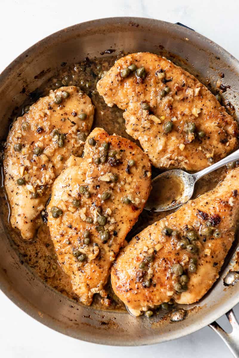pan fried chicken breasts with a lemon garlic caper pan sauce in a pan