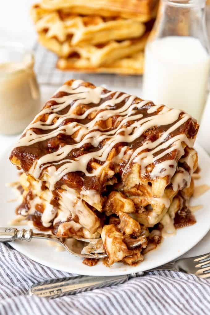 a stack of waffles drizzled with brown sugar cinnamon glaze and maple cream cheese icing