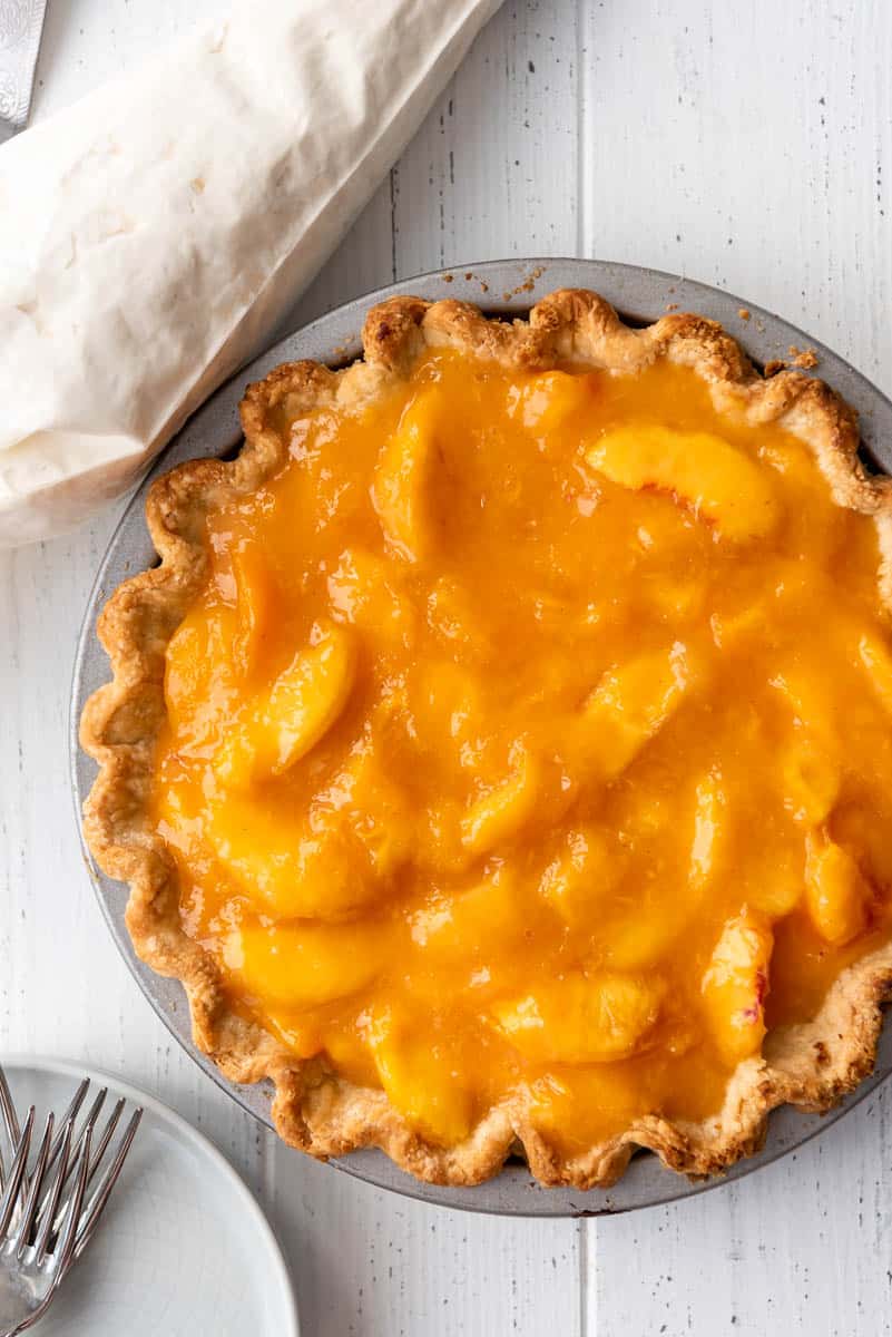 a whole fresh peach pie in a metal pie tin