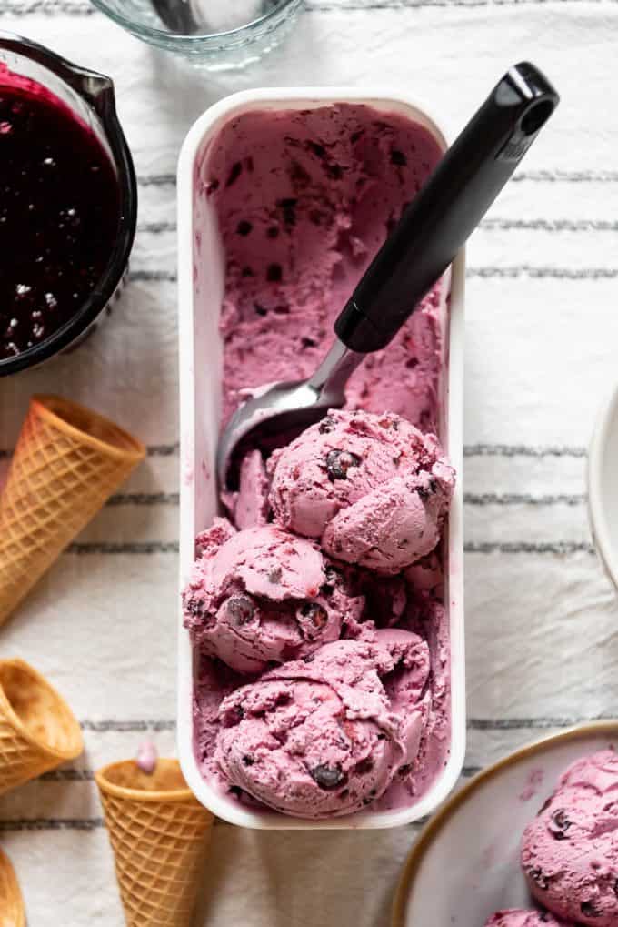 scoops of naturally purple huckleberry ice cream in a white container