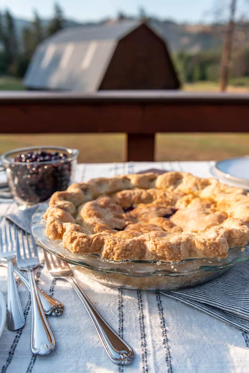 a huckleberry pie in a glass pie plate in front of a barn in Montana