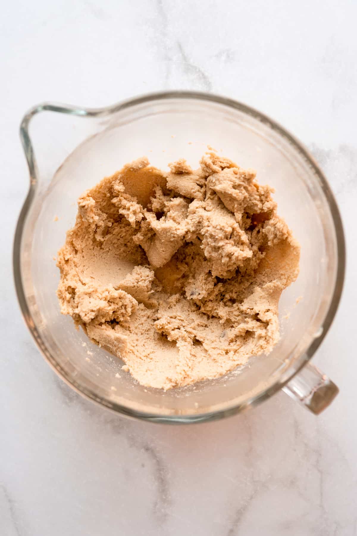 Butter and sugar are creamed together in a large glass measuring bowl. 