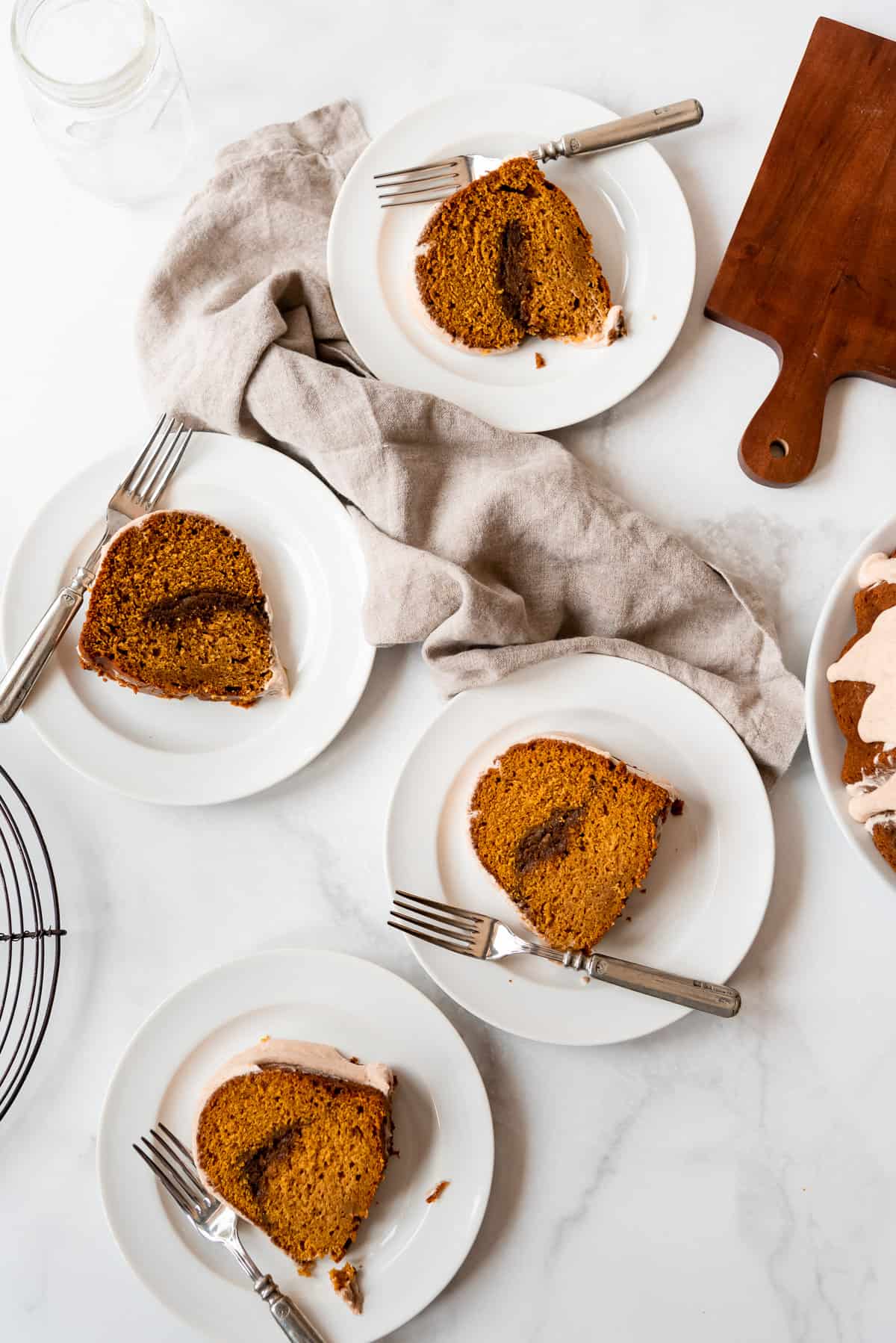 Slices of spiced pumpkin bundt cake are placed on individual plates and have silver forks placed to the side of each piece. 