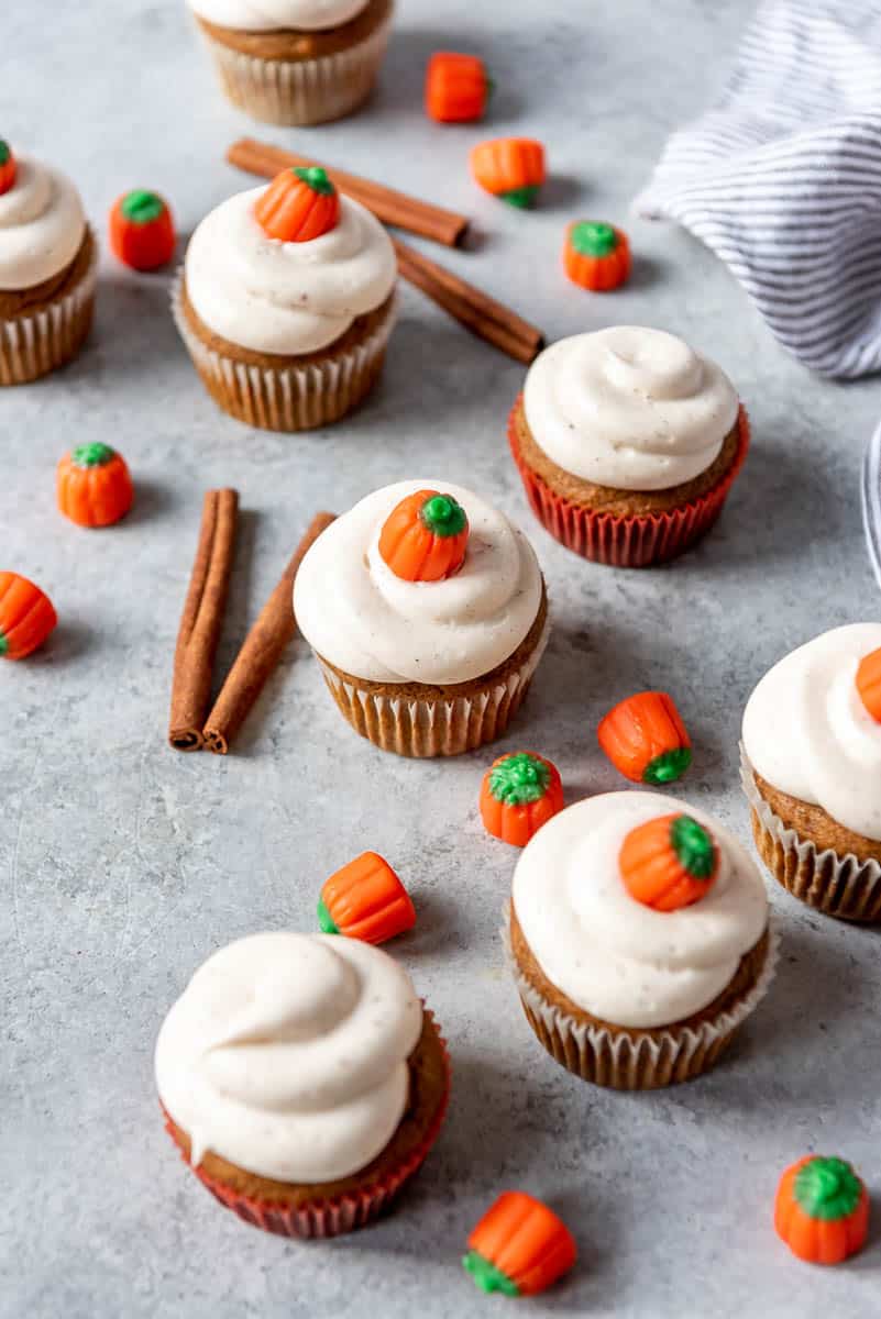 moist pumpkin cupcakes surrounded by candy pumpkins and cinnamon sticks.