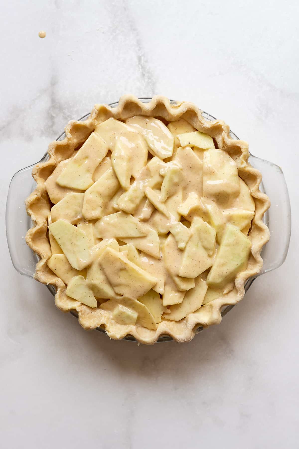 Sliced apples in a pie crust before baking.