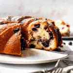 Blueberry Sour Cream Coffee Cake on a white cake tray with pieces cut out.