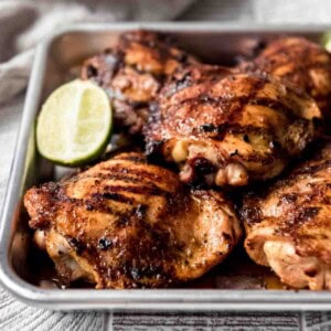 Grilled chicken brushed with honey glaze on a baking sheet.