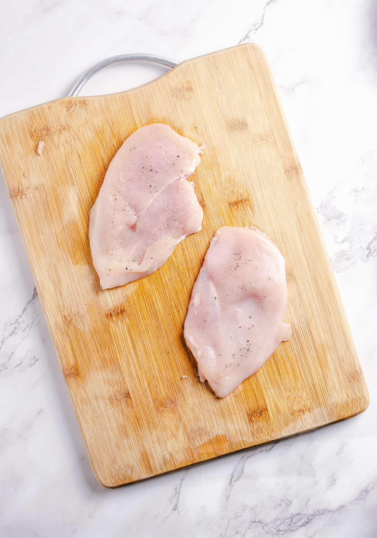 Raw chicken breast on a cutting board.