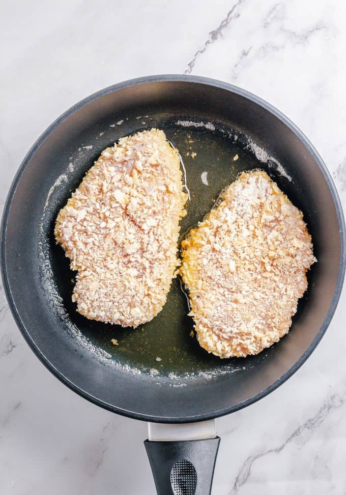 Frying breaded chicken breasts in a pan of oil.