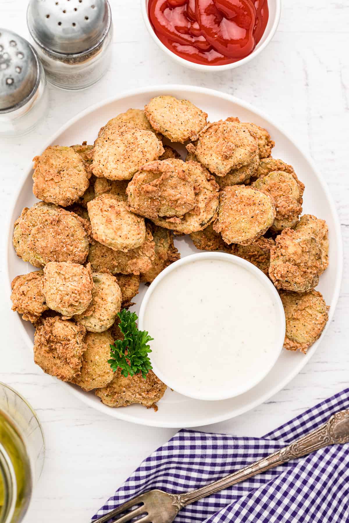 A plate of fried pickles with a bowl of ranch dipping sauce.