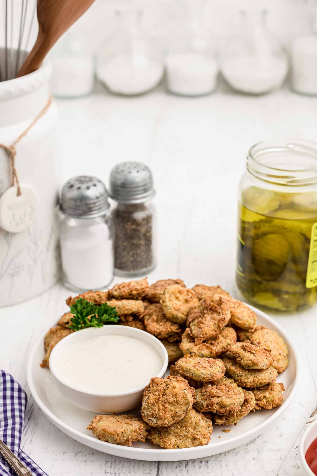 A plate of fried pickles with a bowl of dipping sauce. 