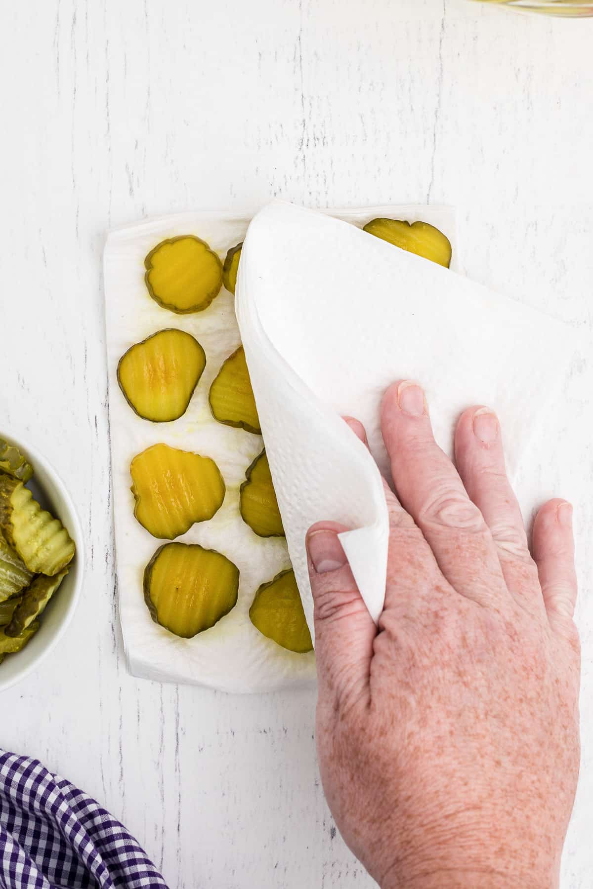 Patting dill pickle slices dry before coating. 