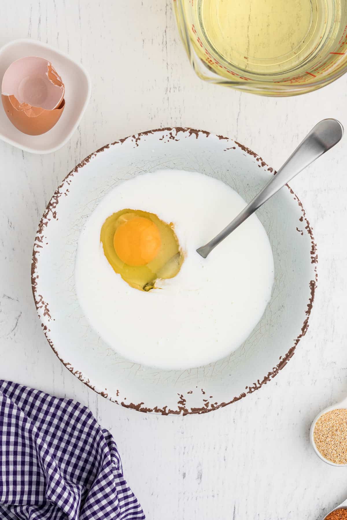 An egg wash is created by combining an egg and milk in a bowl. 