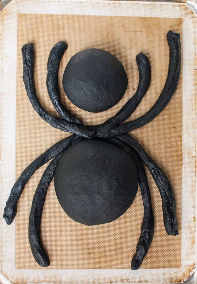 Assembling a spider bread bowl made with activated charcoal powder for Halloween.