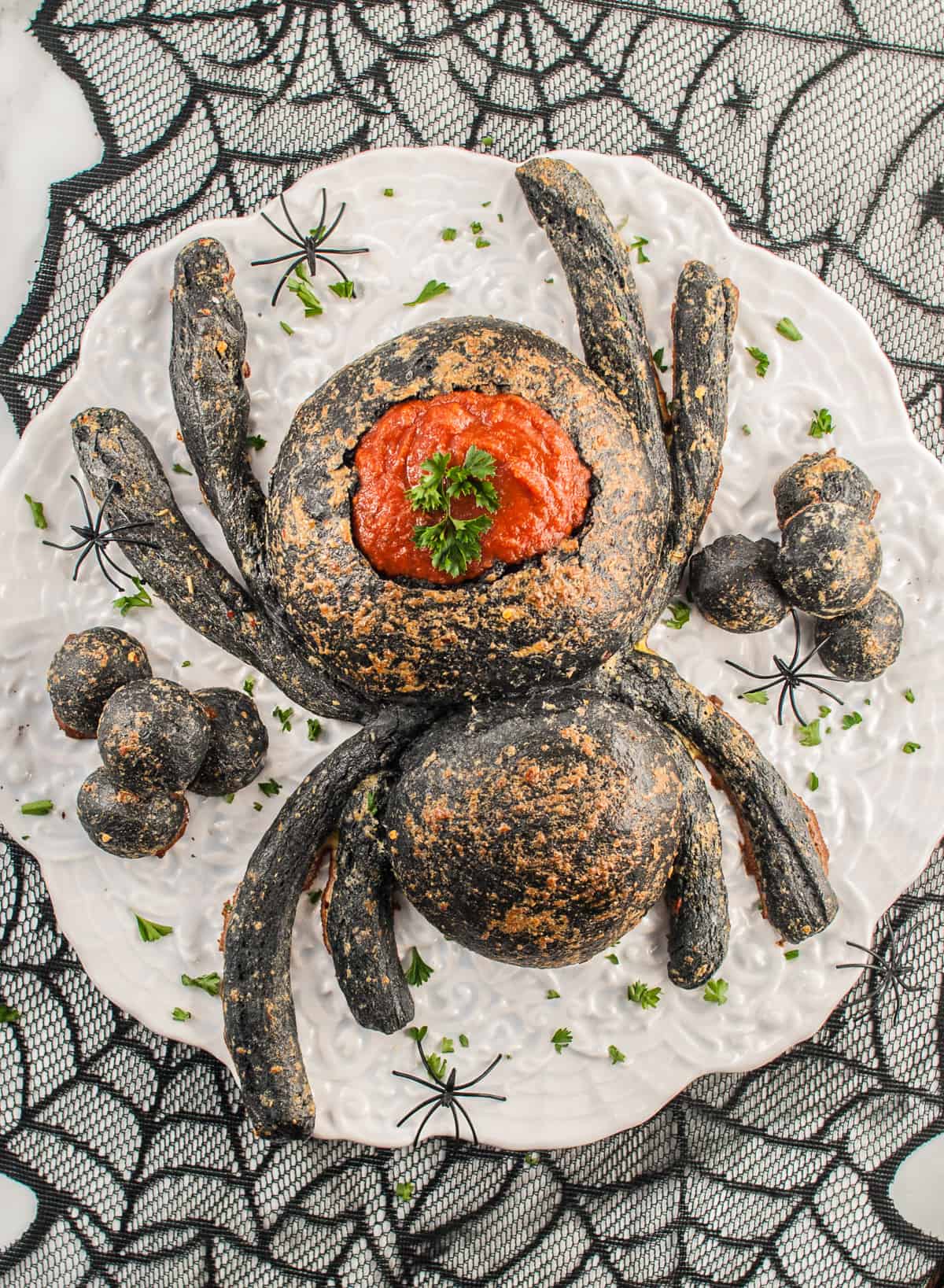 A black spider bread bowl filled with marinara sauce for dipping.