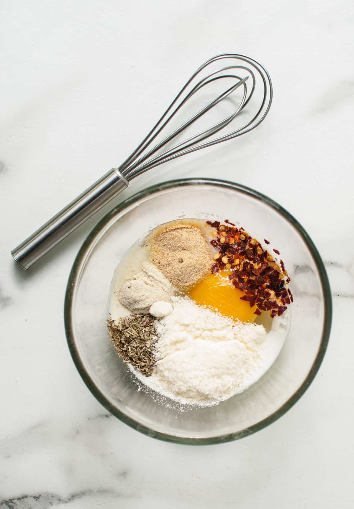 Ingredients for a garlic, herb, parmesan egg wash in a bowl.