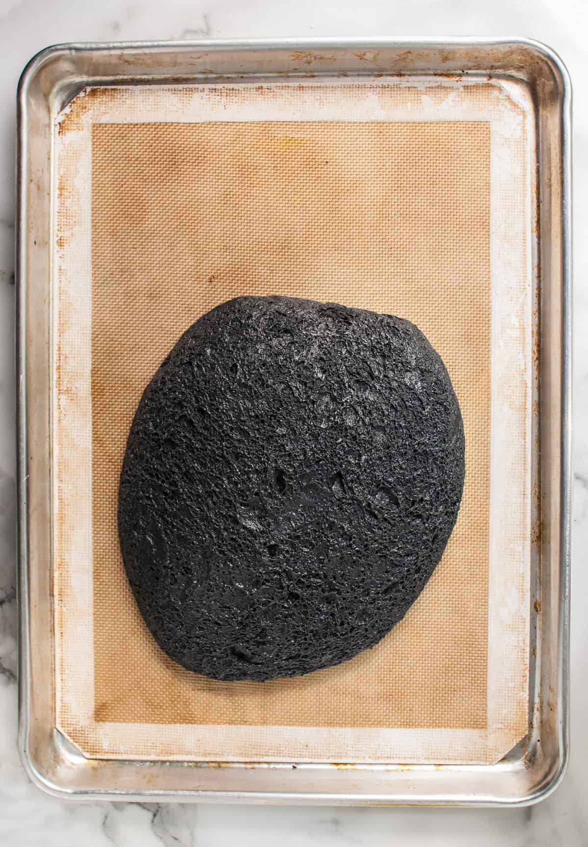 Black bread dough made with activated charcoal powder turned out onto a baking mat.