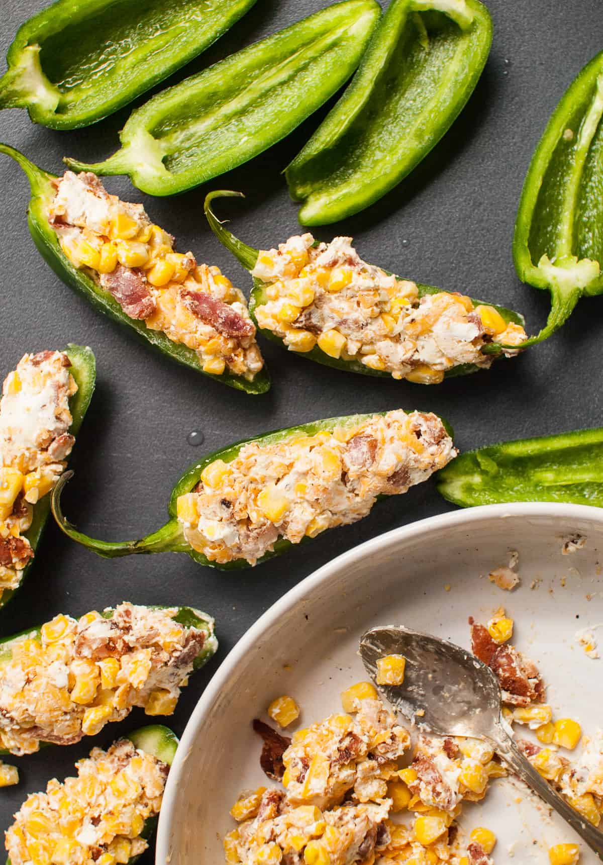 A close shot of jalapeno halves filled with a corn, cream cheese, and bacon filling.