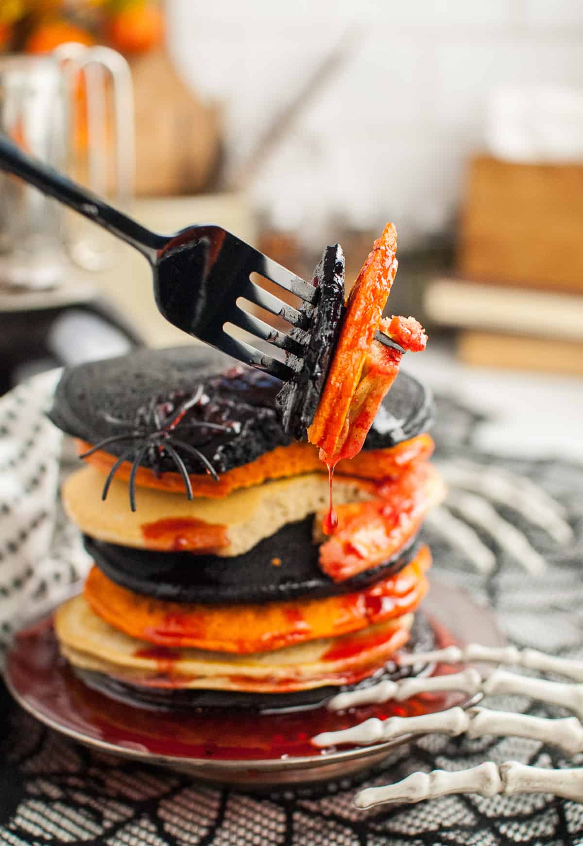 A fork with bites of Halloween black and orange pancakes on it.