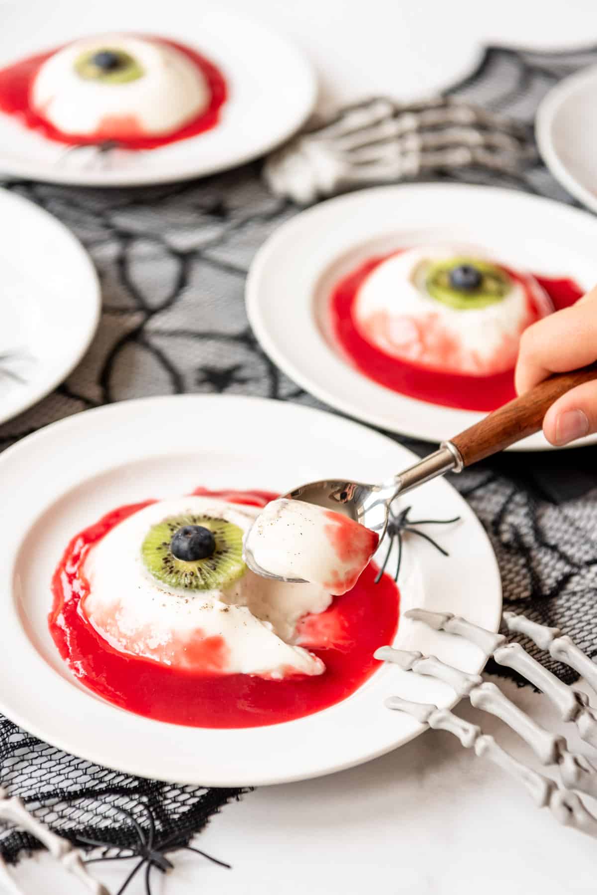a spoon lifting up a bite of bloody panna cotta eyeball.