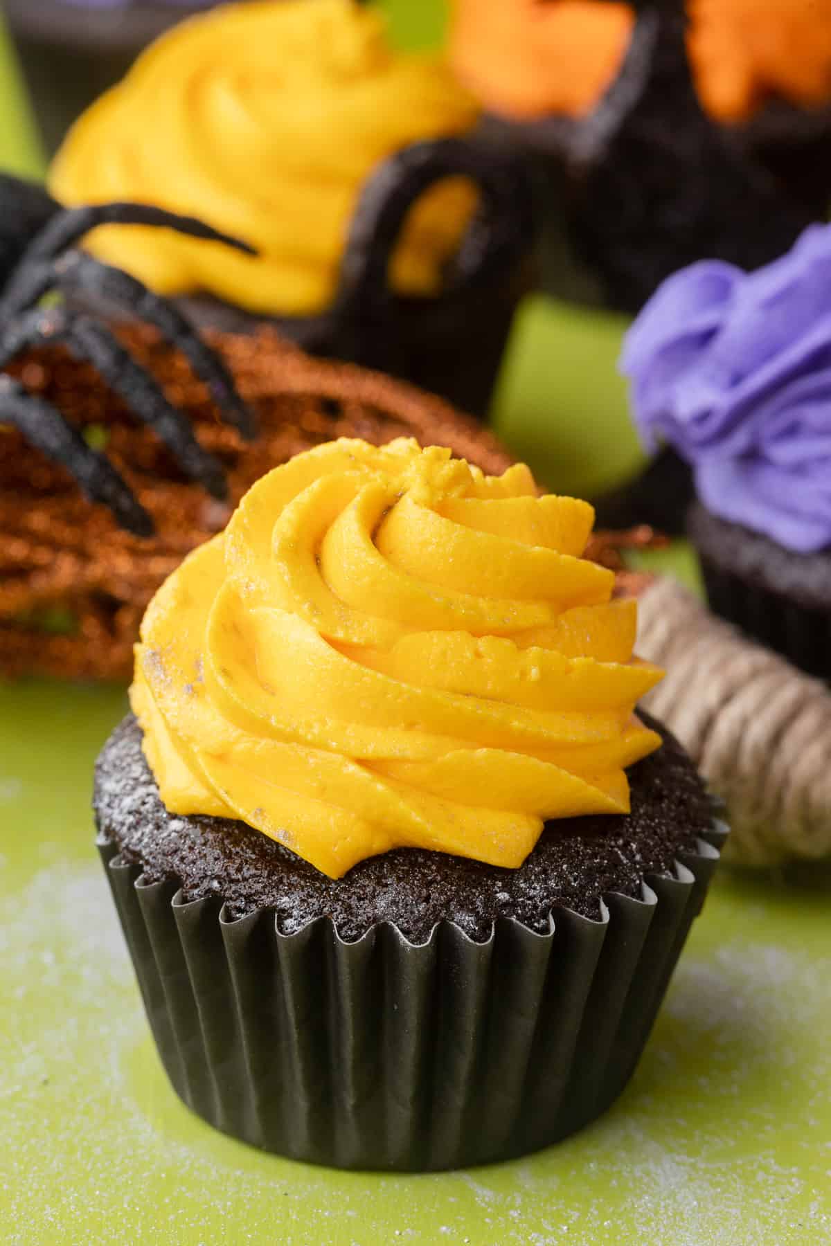 A chocolate cupcake with a swirl of yellow buttercream frosting on top.