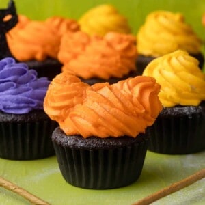 Hocus Pocus cupcakes with orange, purple, and yellow frosting on a ground background.