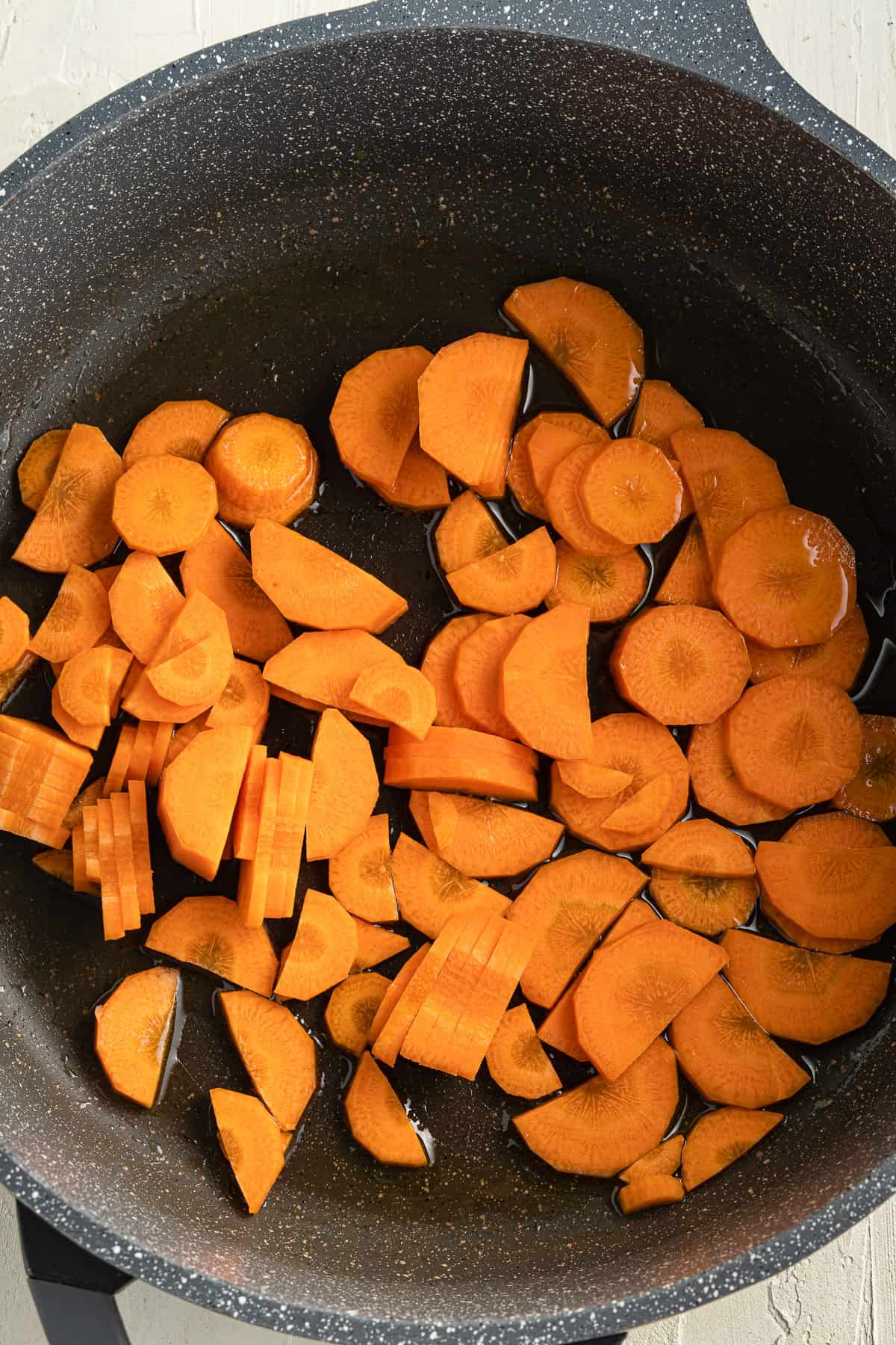 Top view of a black pot with chopped carrots in it.